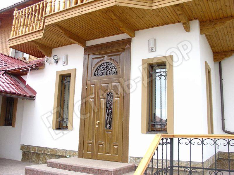 Входная дверь для загородного дома с отделкой массивом ценных пород дерева, стеклом и ковкой